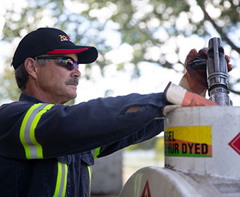 Fuel truck delivery driver filling an oil tank at a customers residence.
